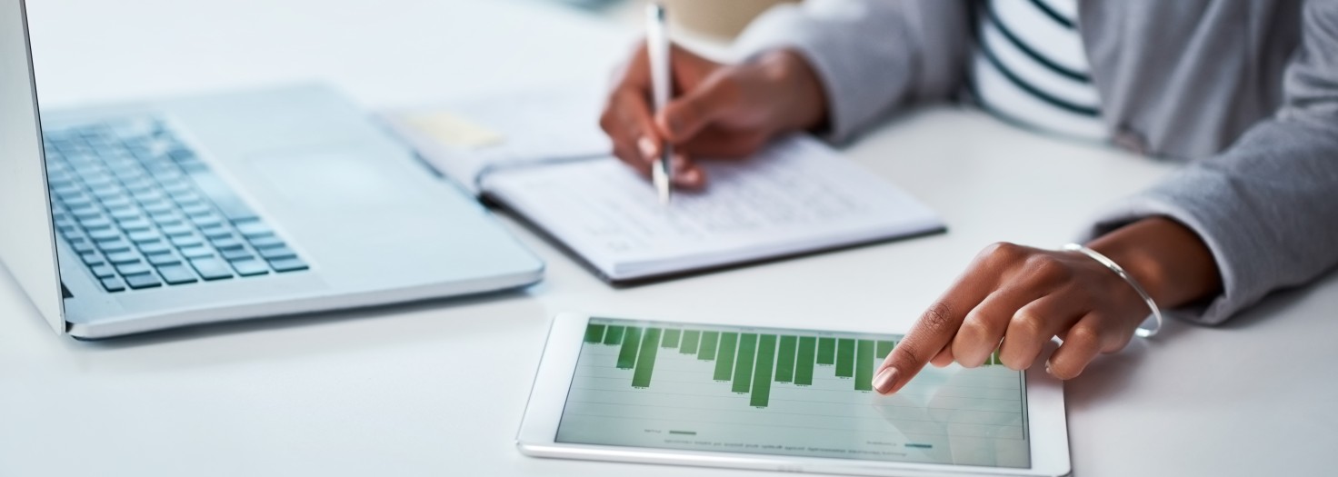 Shot of an unrecognizable businesswoman using a digital tablet with graphs on it in a modern office