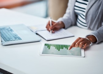 Shot of an unrecognizable businesswoman using a digital tablet with graphs on it in a modern office