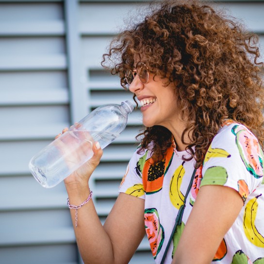 a young woman drinking water from a bottle on the street