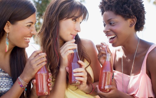 Smiling women drinking soda together