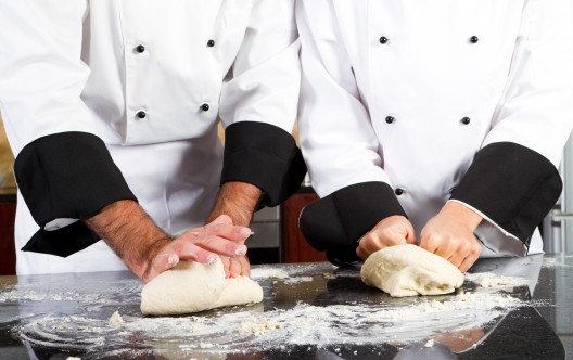 professional chef hands kneading bread dough on kitchen counter