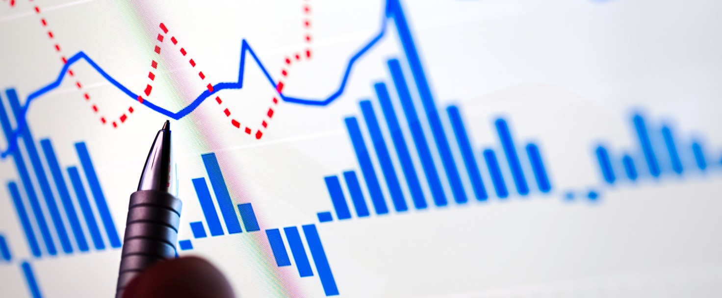 stock chart on computer monitor is growing, hand with pen is pointed on lower peak of graph