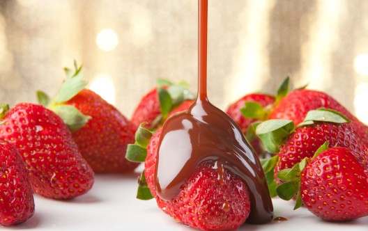 Chocolate being poured over strawberries close up