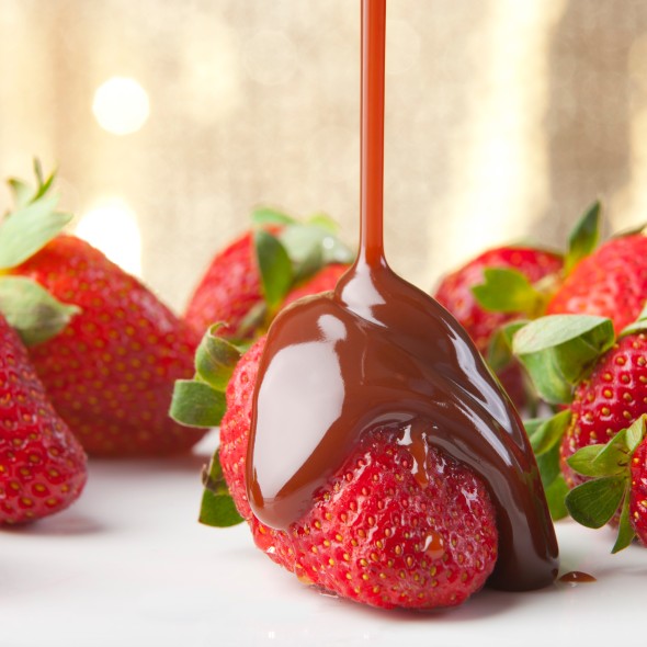 Chocolate being poured over strawberries close up