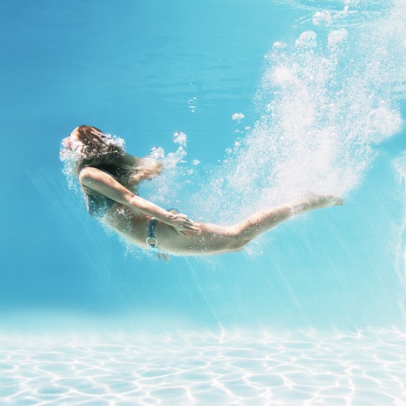Woman swimming underwater in swimming pool