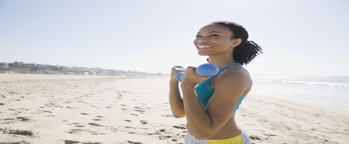 Woman lifting dumbbells on beach