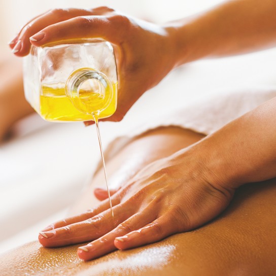 Woman pouring massage oil on spa client
