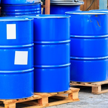Many blue barrels standing on wooden pallets on a chemical plant