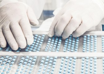Worker inspecting pills on blisterpack conveyer belt