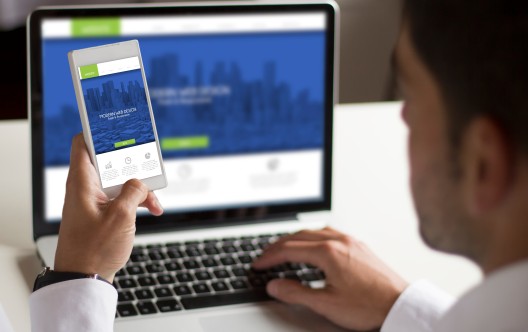 businessman testing responsive at work with smartphone showing website on screen. All screen graphics are made up.