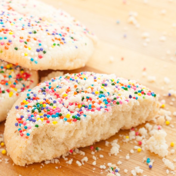 Studio photo of homemade sugar cookies with color sprinkles. Selective focus on top of broken cookie in center.