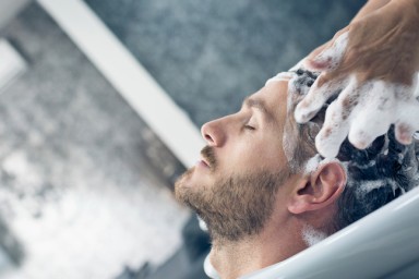 Young man getting his hair washed by a female hairdresser.