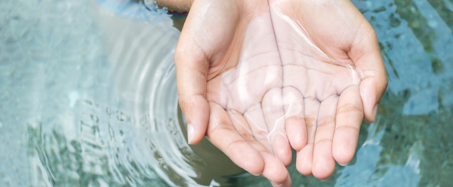 Clear natural water in woman hands.