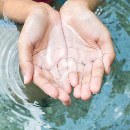 Clear natural water in woman hands.