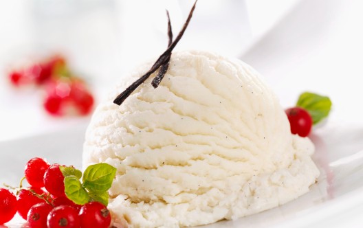 A scoop of vanilla ice cream with fresh redcurrants