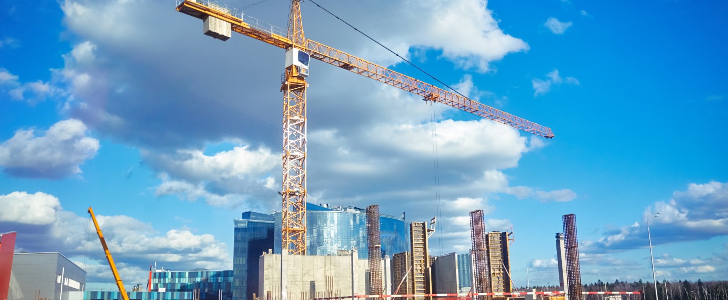 Construction site crane at blue sky clouds background, through glass