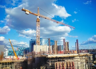 Construction site crane at blue sky clouds background, through glass