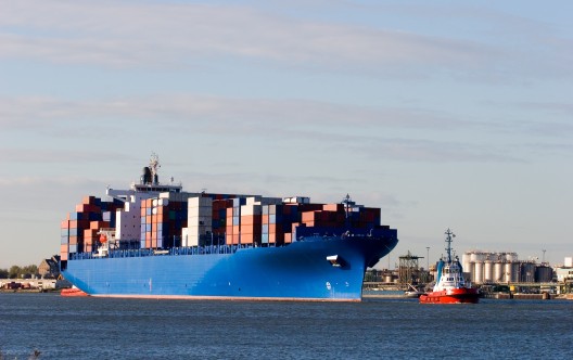 Blue containership with containers being tugged in the Rotterdam harbour