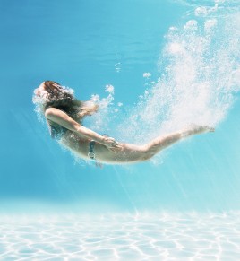 Woman swimming underwater in swimming pool