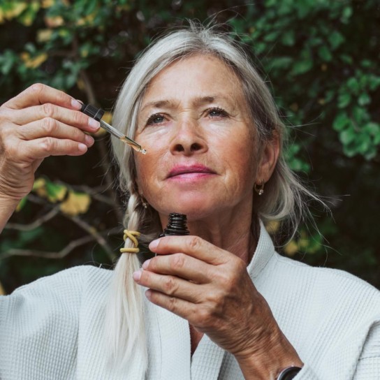 Beautiful older woman doing her skin care routine outdoors. Standing in the garden, using skin serum for mature skin.
GettyImages-2178666133.jpg