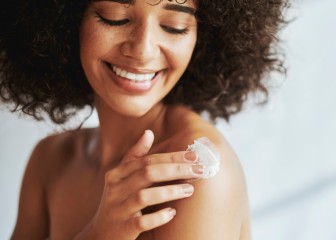 Black woman, cream and skin with smile, shoulders and self care, start and morning in home. Woman, product and skin for cosmetics, healthy glow and natural aesthetic for self love, health or beauty
GettyImages-1460122296.jpg