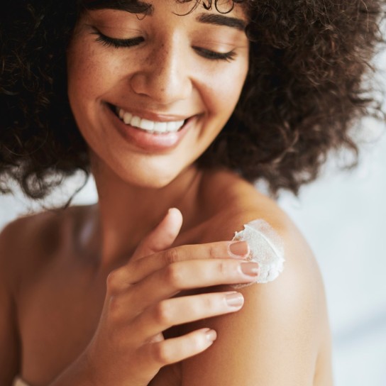 Black woman, cream and skin with smile, shoulders and self care, start and morning in home. Woman, product and skin for cosmetics, healthy glow and natural aesthetic for self love, health or beauty
GettyImages-1460122296.jpg