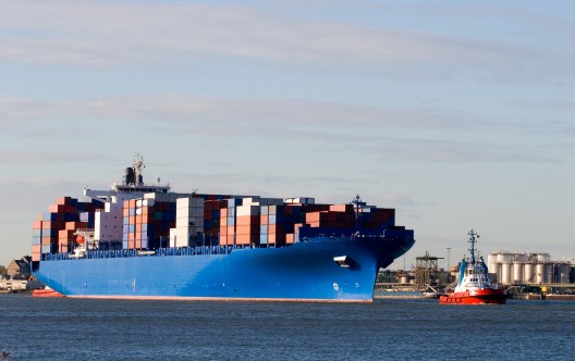 Blue containership with containers being tugged in the Rotterdam harbour