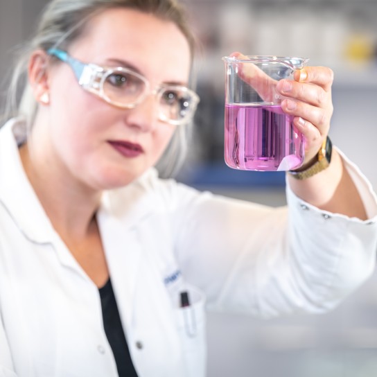Female chemist checking the liquid in a test laboratory bottle in the application kitchen, Essen, Germany