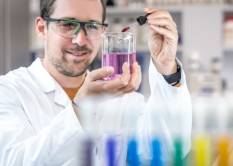 Male chemist checking the liquid in a test laboratory bottle in the application kitchen, Essen, Germany