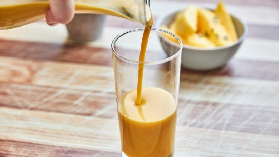 Mango smoothie with on the background pieces of chopped mango in a bowl.
