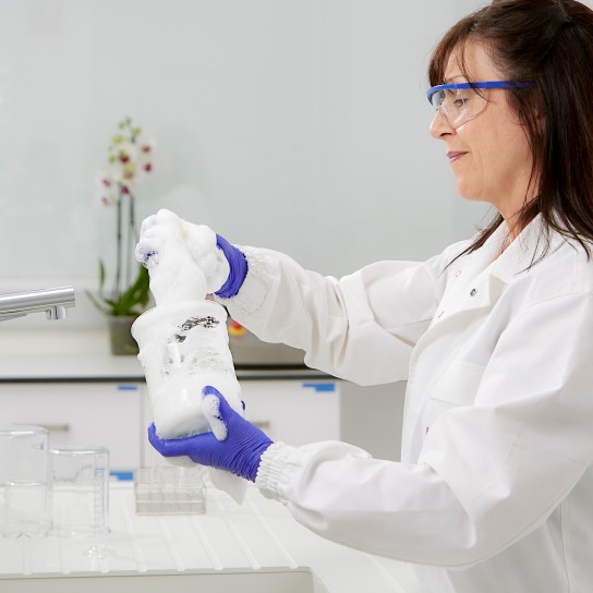 Woman smiling while washing a lab glass in the laboratory