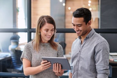 Young woman and man looking at a tablet.