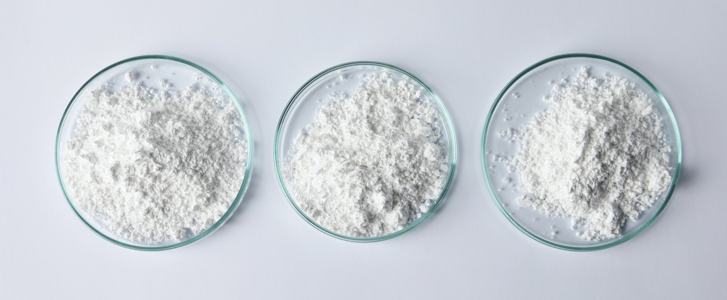 Petri dishes with calcium carbonate powder on white table, flat lay