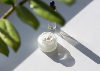 Cosmetic cream and serum, flower leaves. Natural hard light, deep shadows.