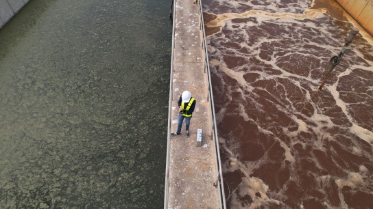 Drone view of Environmental Specialist walking through and work inspecting water treatment pond