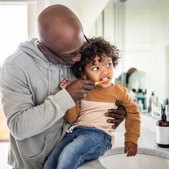 Father helping toddler brush teeth in bathroom
GettyImages-1838408022.jpg