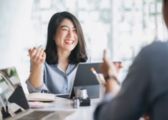 Smiling woman at a desk holding a pen