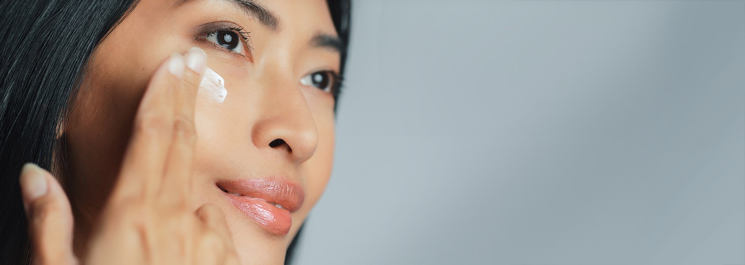 Woman applying lotion on her face