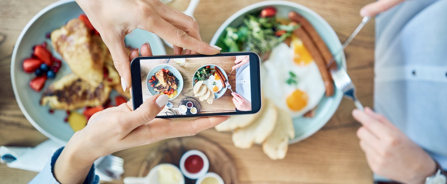 Woman taking photo of breakfast served in cafe. Couple having meal together
