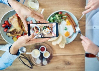 Woman taking photo of breakfast served in cafe. Couple having meal together