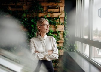 Businesswoman in green office looking out of window