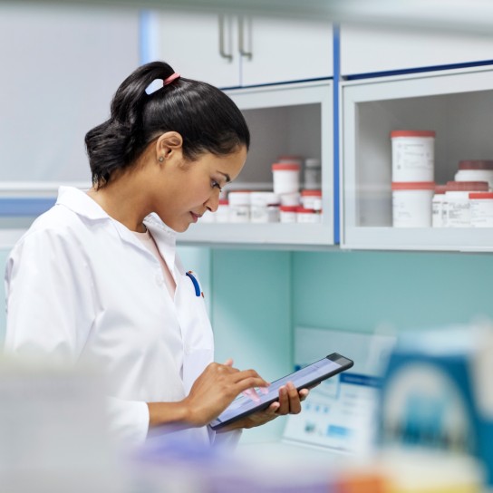 Young scientist using digital tablet while researching in laboratory. Confident female homeopath is wearing lab coat. She is working in hospital.