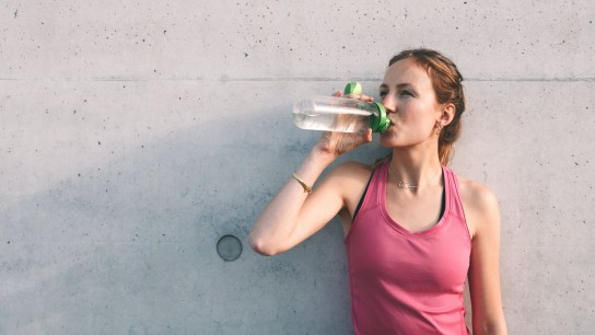 Woman drinking sport nutrition out of a bottle after a workout