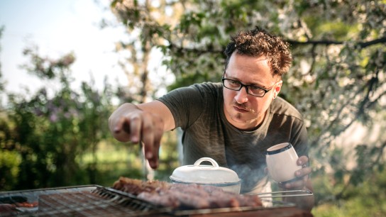 Men are cooking for family having barbecue party in garden on summer