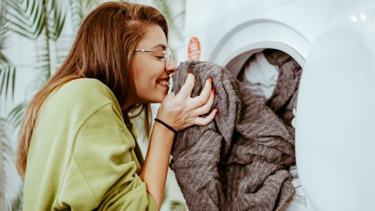 Young woman takes laundry out of the washing machine