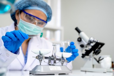 Lab technician taking pill from petri dish with lancet, pharmaceutical industry