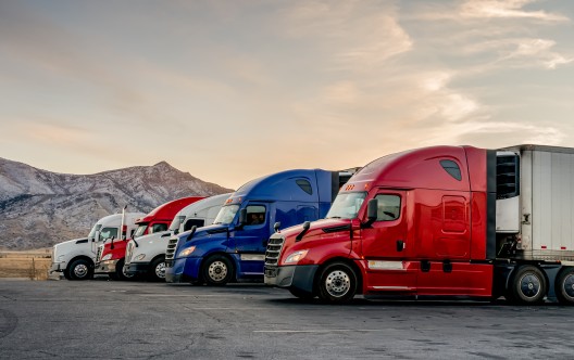 Red, white and blue parked trucks lined up at a truck stop