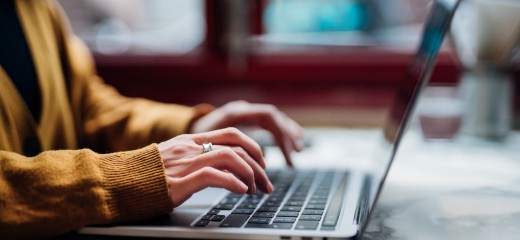 Side view of female hand typing on laptop keyboard. Freelancer working with laptop at cafe. Technology and flexible working.