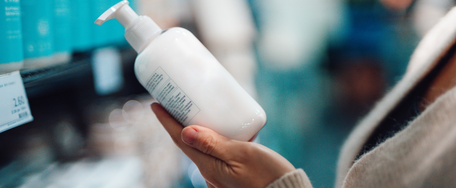 Young woman doing grocery shopping in supermarket. Plastic bottle mockup for packaging design.