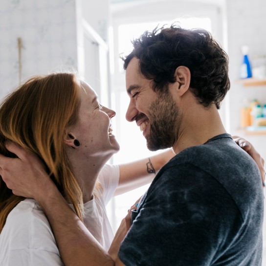 A couple  affectionately embracing each other and smiling after meeting on an online dating app.